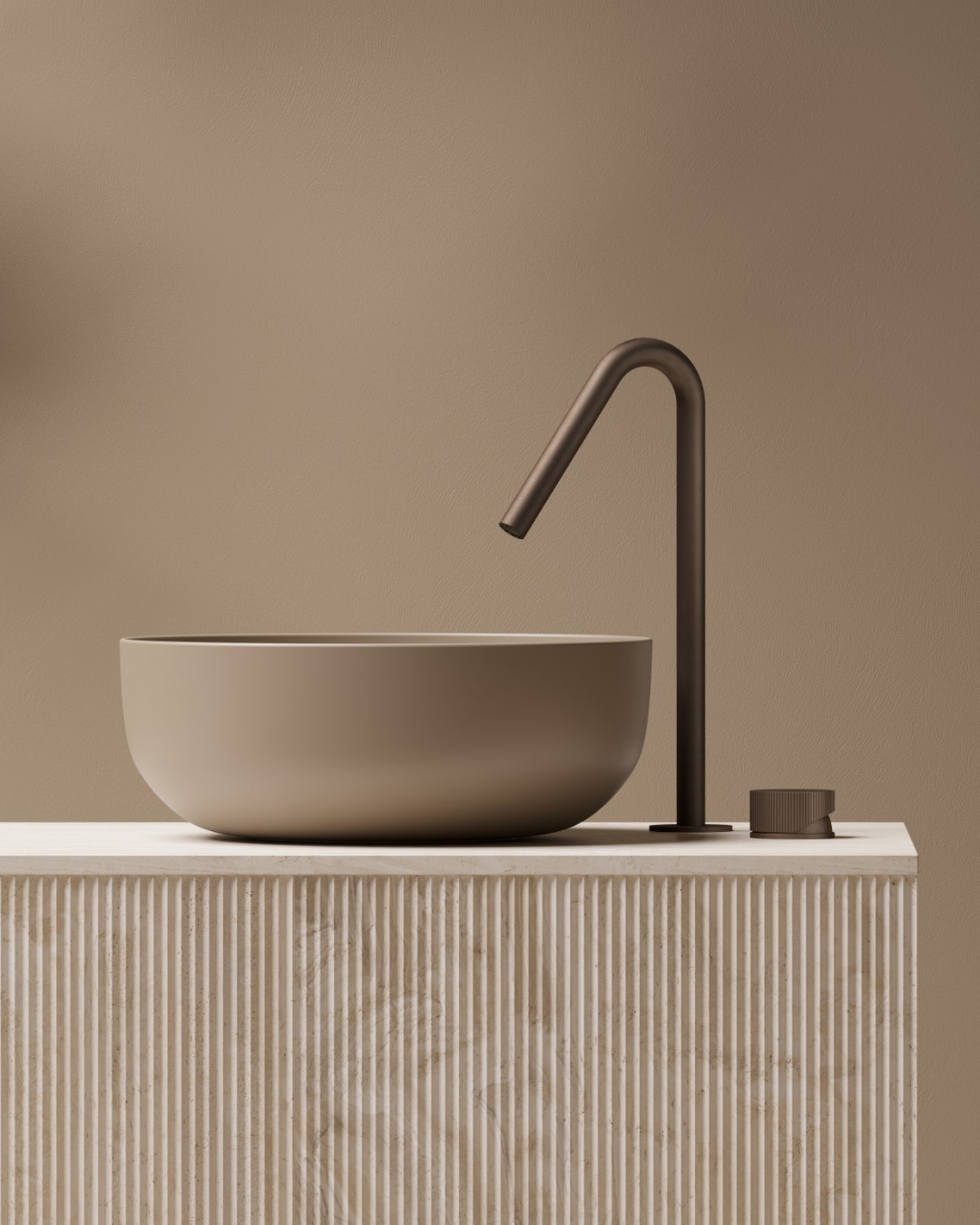 Hotbath Guy wastafelkraan in Tuscan Bronze naast een beige waskom op een licht meubel met verticale groeven.