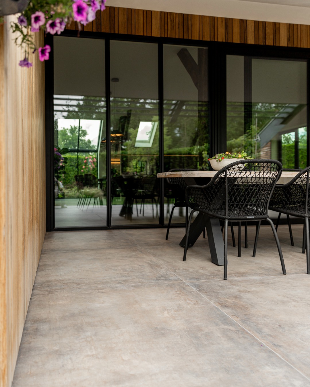 Grootformaat terrastegels in grijsbruine tinten op een overdekt terras bij Van der Rijt Tegels Uden