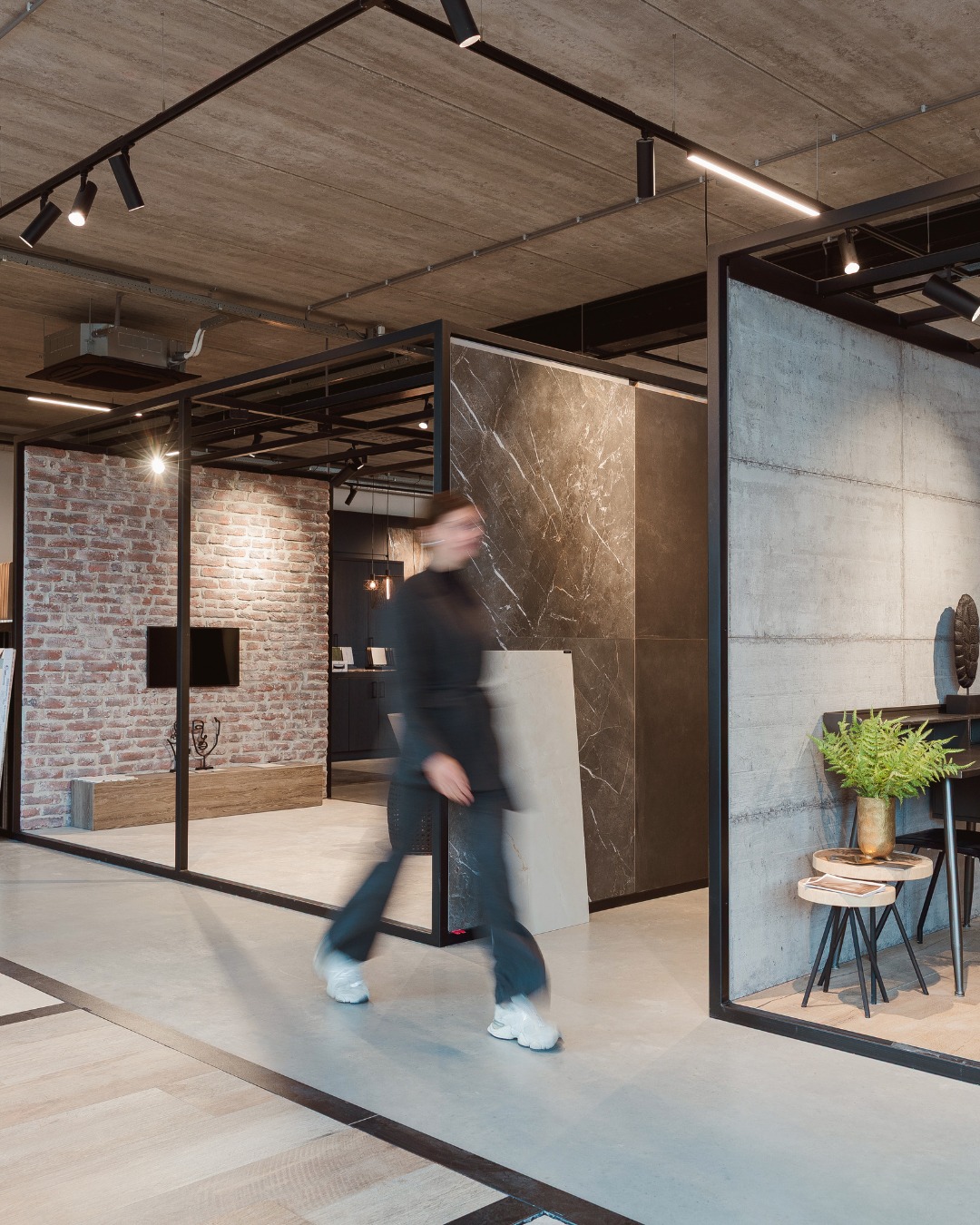 Showroom van Van der Rijt Tegels Uden met bruine marmerlook, grijze betonlook en zwarte frames.