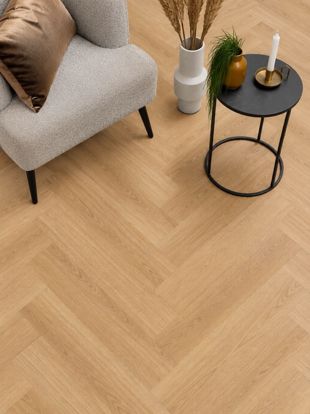 Visgraat-pvc-vloer in lichte houtkleur naast een grijze fauteuil bij Yuvam Bouwmaterialen in Rotterdam
