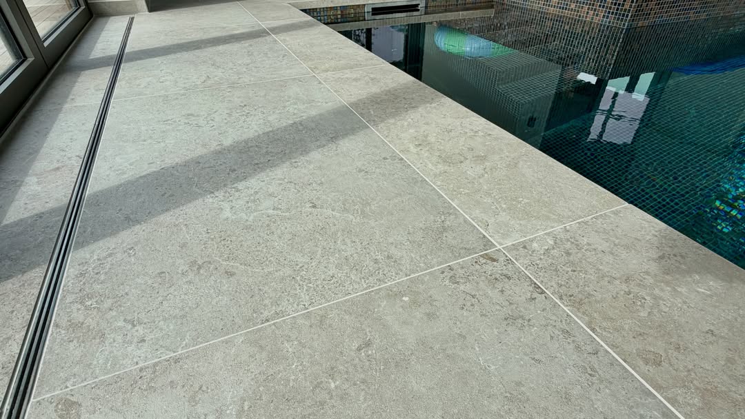 Grijze zwembadrandtegels met natuurlijke tekening rondom een binnenzwembad, verzorgd door Stone Concepts in Naaldwijk