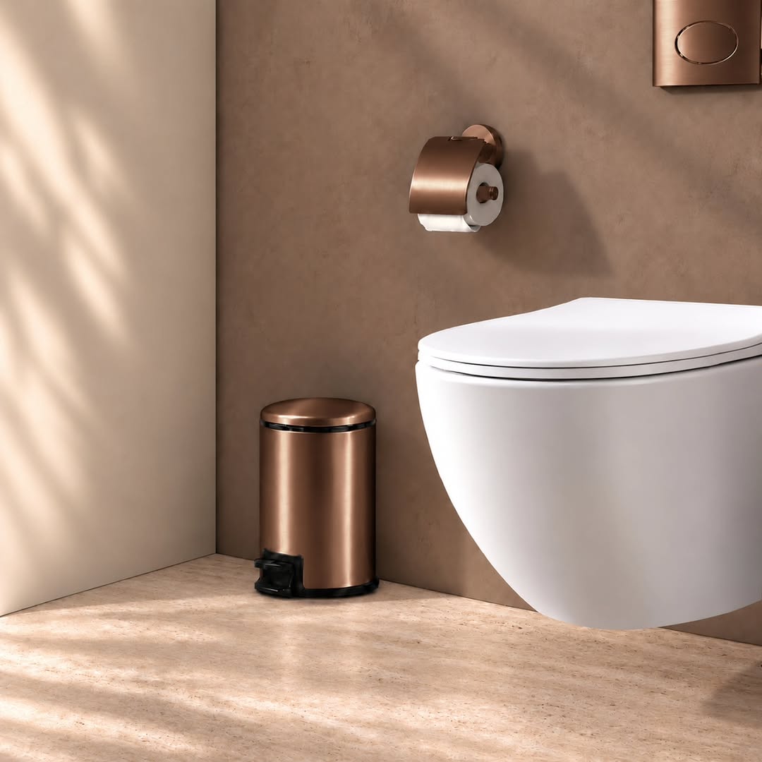 Tobin pedaalemmer in bronskoperkleur naast een wit hangtoilet met bijpassende accessoires bij Wiesbaden