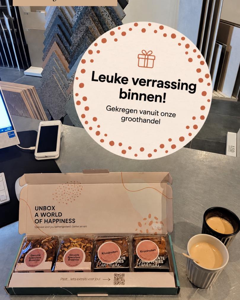 Browniebox op de balie naast twee koppen koffie en tegelrekken bij TegelStore.nl in Roosendaal